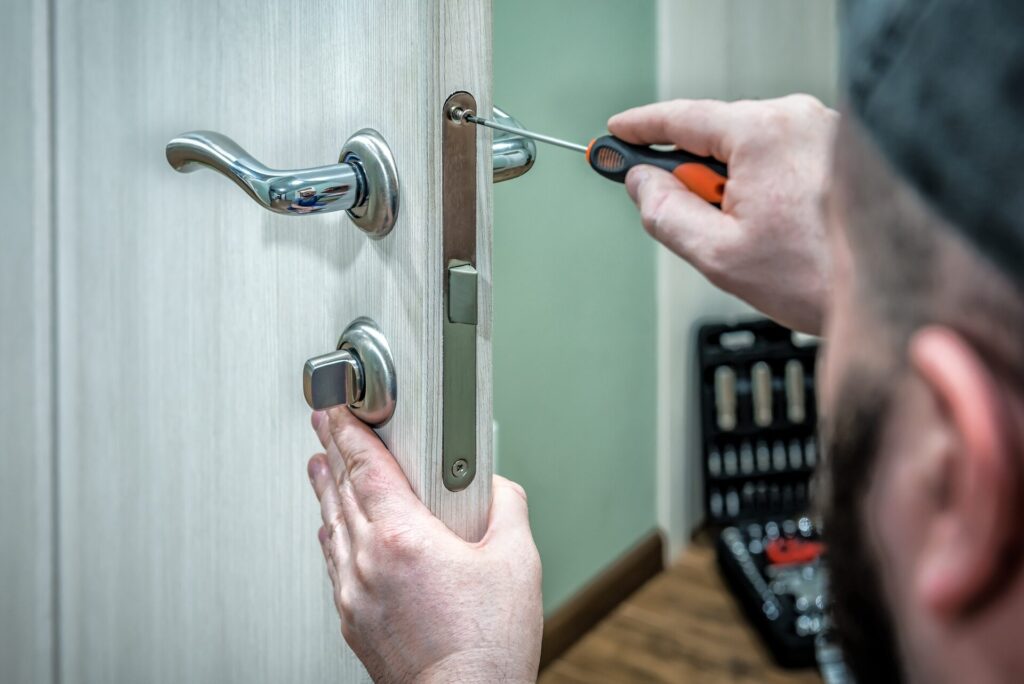Rekey or replace locks after a break in image showing a locksmith changing a lock cylinder for home security.